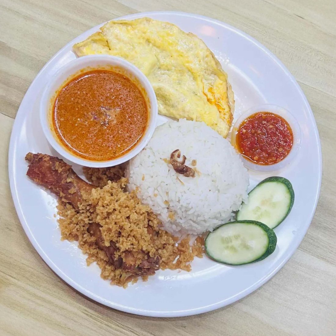 A plate of rice, fried chicken, curry, omelette and sambal at Kekwa Cafe